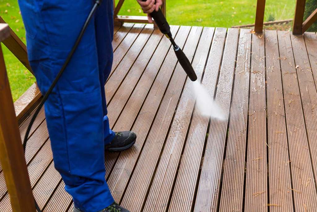 Man power washing wooden deck
