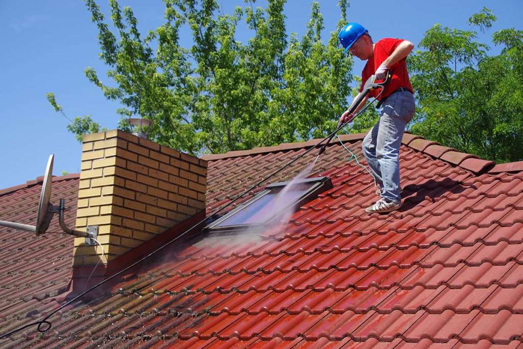 Man power washing the roof of a hosue